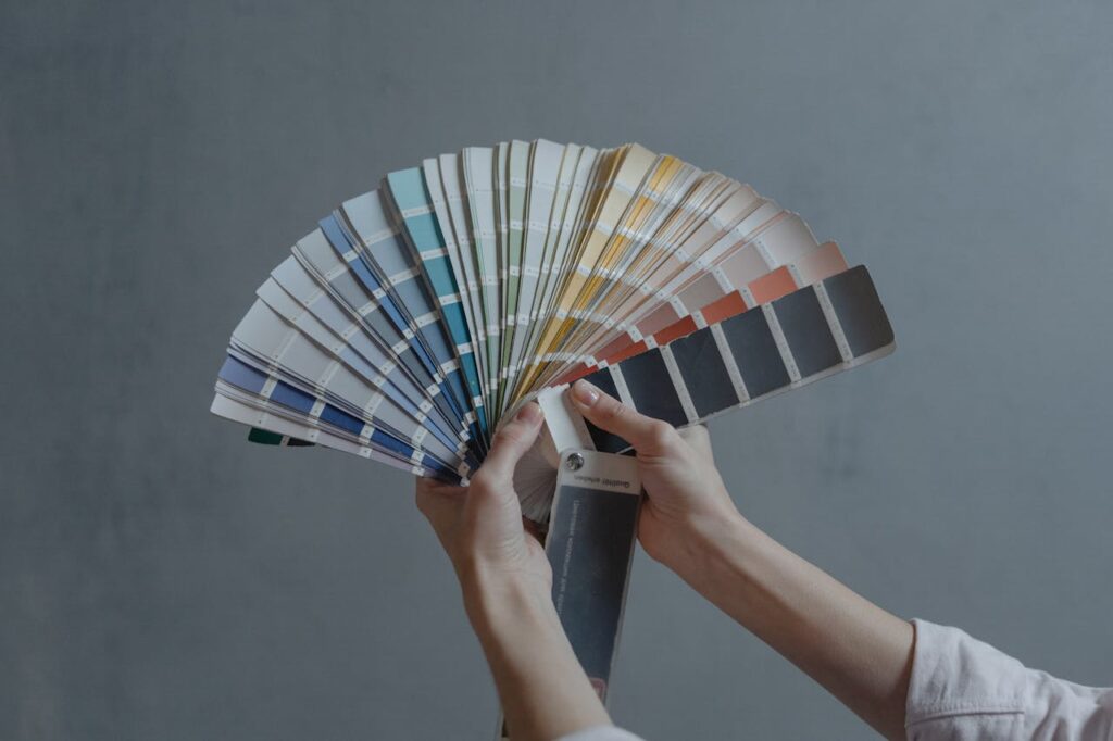 Hands holding a large fan of paint color swatches.