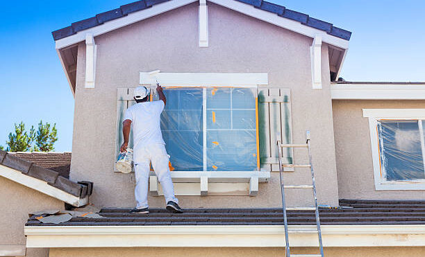 Busy House Painter Painting the Trim And Shutters of A Home.