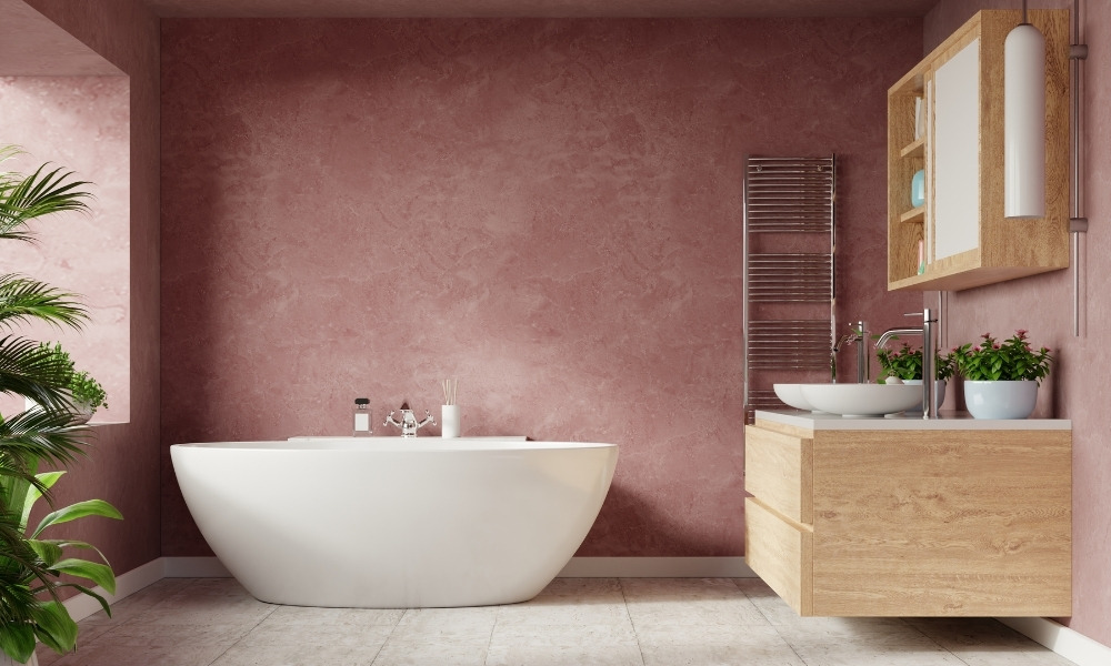modern, white, oval-shaped freestanding soaking bathtub against a textured pink wall