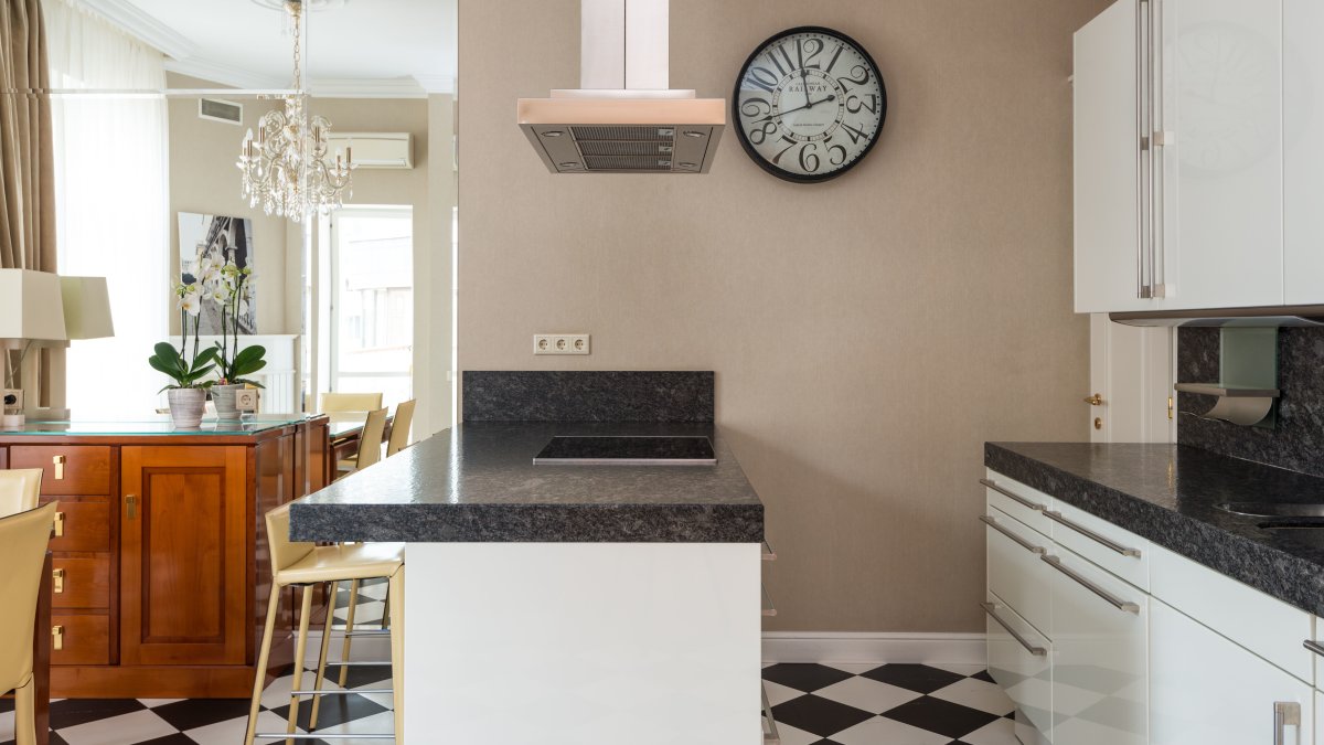 Light, simple kitchen with tiled floor and island counter next to dining table