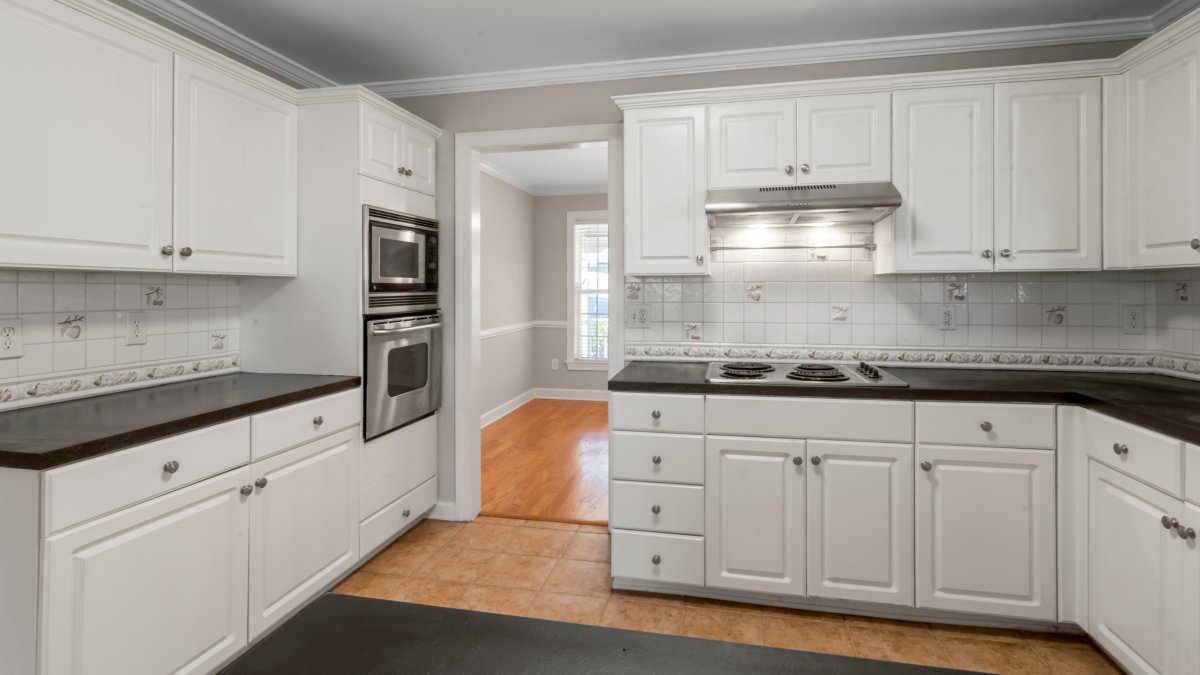Spacious white kitchen featuring stainless steel appliances and dark countertops